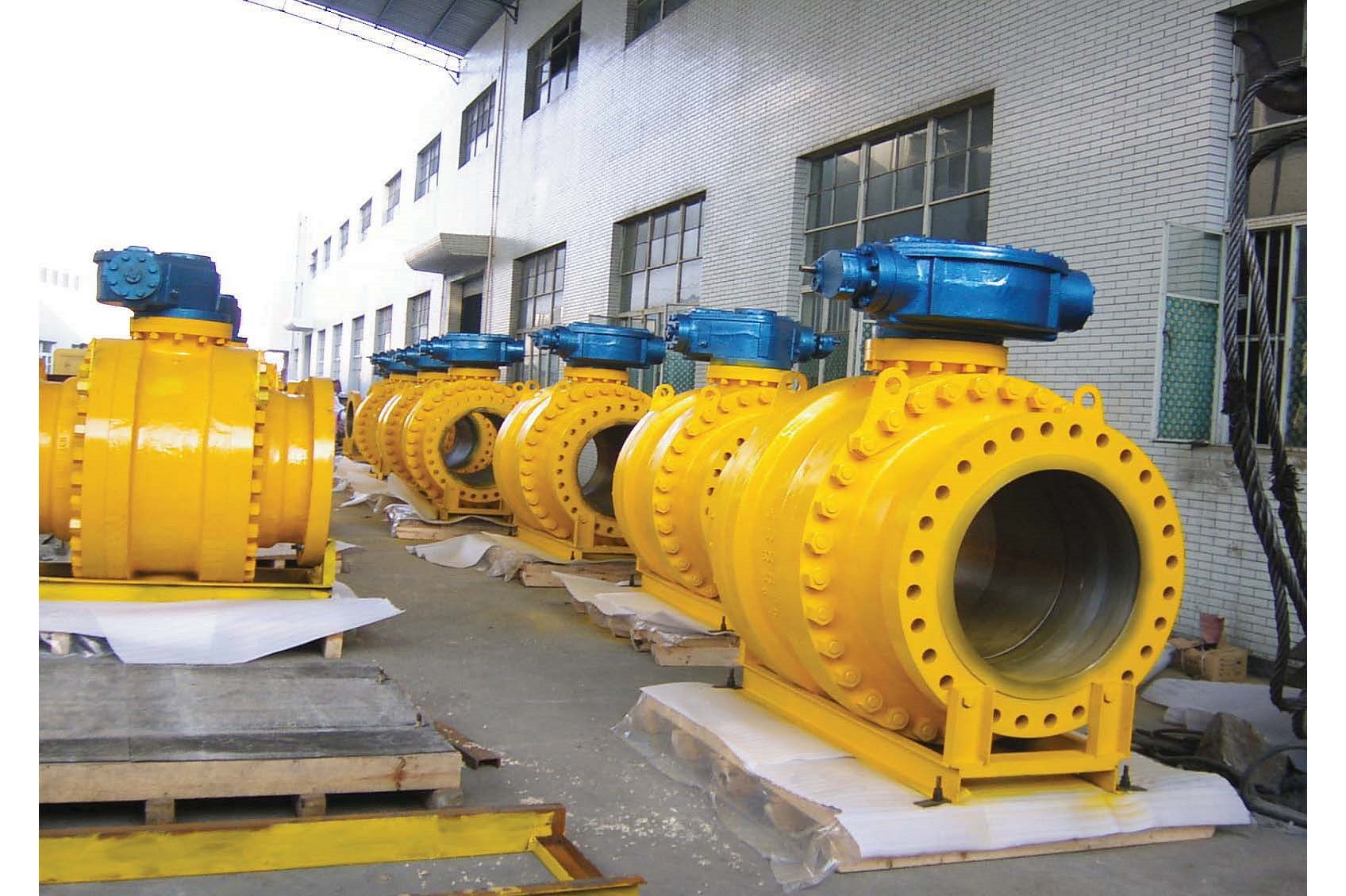 Yellow painted industrial ball float valves arranged in a workshop for dispatch